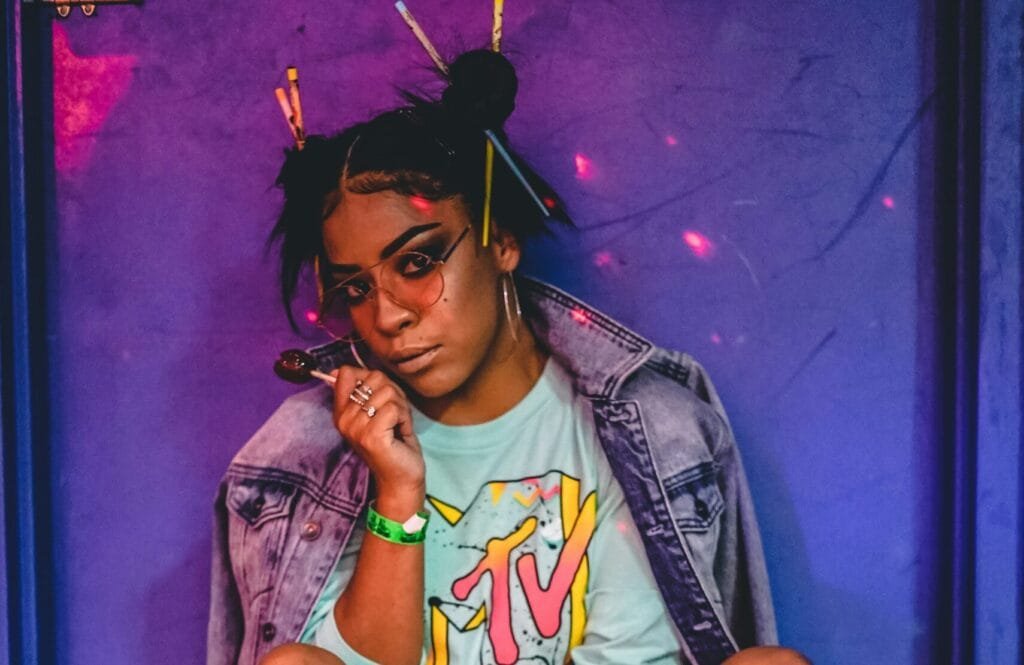 woman sitting wearing roller skates and jacket while holding lollipop