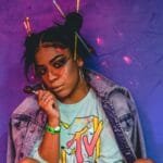 woman sitting wearing roller skates and jacket while holding lollipop