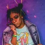 woman sitting wearing roller skates and jacket while holding lollipop